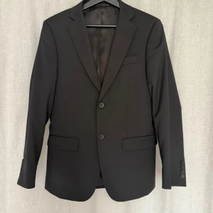 Svart kostym från Dressmann - Svart kostym ifrån Dressman. Kavajen är i storlek 44-short och byxorna i storlek 30/30. Nypris ca 4000