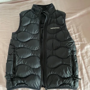 Peak Performance Väst - Snygg svart dunväst från Peak Performance. Perfekt att slänga över en hoodie för extra värme. Klassisk och stilren design. Inga defekter finns på den och syns nästan inte att den varit använd. Hör av dig om du har någon fråga.