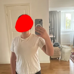 Vit t-shirt med färgglatt tryck bak - Vit t-shirt i klassisk modell med rund hals och korta ärmar. Baksidan har ett stort färgglatt tryck med olika symboler och texten 'BVALID' i mitten, vilket är namnet på själva märket. Skön och enkel stil som passar till det mesta. Materialet känns mjukt och lätt.