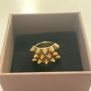 Guldig statementring från Edblad i strl S - Cool och snygg ring från Edblad i guldtonad metall med flera spetsiga nitar på ovansidan. Perfekt för dig som vill ha ett smycke som syns och är perfekt för att lyxa till en outfit! Ringen är använd i några månader och har tappat lite färg på baksidan men ingenting som syns när man har den på! På annars så ser den som ny ut! Nypris 399 kr. Den är i storlek S/16,8⭐️💍låda kommer till och pris kan diskuteras