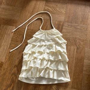 Trendig topp från Gina Tricot💛🦕 - En trendig gul volang topp från Gina Tricot, som är nyskick och aldrig använd! En liten, liten sminkfläck på insidan av tröjan som inte syns och som säkert går bort, se bild 3.  Mer åt det mindre hållet i storlek, så folk med S kan absolut ha den också! Köparen står för frakt! 