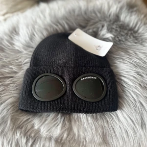 C.P. Company mössa  - Säljer min CP Company mössa i svart. Den är i princip ny, men tyvärr fick den en liten repa på vänster öga när den kom med posten (se bild 🔎). Jag är lite noggrann, vill inte ha nåt skadat, så därför får nån annan en chans till bra pris! 👌