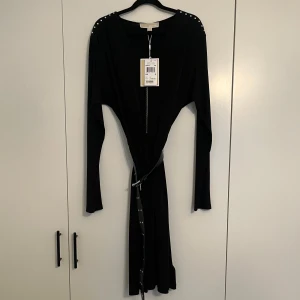 Svart klänning Michael Kors  - Helt ny svart långärmad klänning från Michael Kors med v-ringning, dragkedja framtill och coola silvernitar på axlarna. Bältet till midjan ingår och har också nitar för extra detalj. Nypris 2099kr men säljer det nu för billigare💗💗buda gärna!