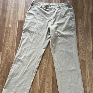 Beige chinos från Rappson of Sweden - Snygga beige chinos från Rappson of Sweden med raka ben och klassisk passform. Byxorna har bälteshällor, knäppning fram och två bakfickor med lock och knapp. Perfekta för en clean och stilren look. Skriv vid intresse😊