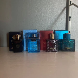 Versace parfymset miniflaskor - Säljer ett set med fyra miniflaskor parfym från Versace: Dylan Blue, Eau Fraîche, Eros och Eros Flame. Flaskorna är i glas och har olika färger som blå, röd och mörkblå. Varje flaska rymmer 5 ml och har exklusiv design med Versace-logga i guld.( FINNS ATT KÖPA INDUVIDUELLT MEN RABBAT OM MAN KÖPER ALLA)