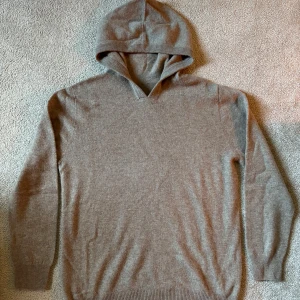 Beige hoodie i kashmir - Mjuk och stilren beige hoodie i kashmir med lång ärm och ribbade muddar.