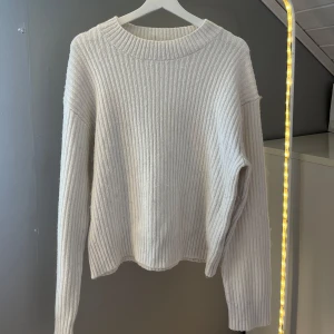 Vit ribbstickad tröja från H&M - Jättefin vit ribbstickad tröja från H&M i storlek S. Tröjan har en rund halsringning, långa ärmar och en relaxed fit. Perfekt för lager-på-lager och enkel att matcha med jeans eller kjol. Supermysig och stilren vibe! Lite noppig därav priset!