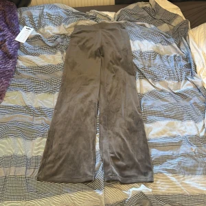Grå mjuka byxor från H&M - Mysiga grå byxor från H&M i storlek 152. De är tillverkade i mjuk polyester med lite stretch och har en rak, något utsvängd passform. Perfekta för en chill och avslappnad stil. Materialet är lent och ger en skön känsla mot huden.