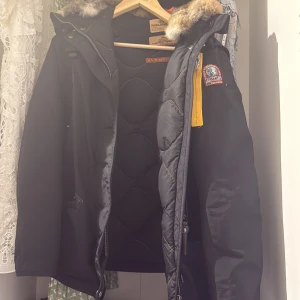 Svart Parajumpers dunjacka med pälsen är borttappad  - Säljer en svart Parajumpers dunjacka med ikonisk gul rem och patch på ärmen. Jackan har huva med päls, flera fickor och snygga detaljer som dragkedja och knappar. Perfekt för kalla dagar och riktigt stilren look. Priset kan diskuteras 