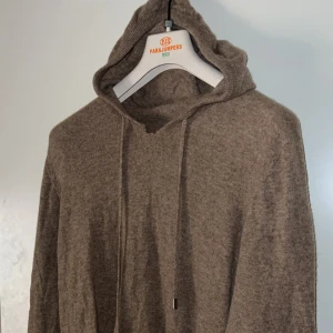 kashmir tröja - Mysig beige stickad hoodie  med huva och snörning. Tröjan har lång ärm och är tillverkad i ett mjukt material som passar perfekt för kyliga dagar. Enkel och stilren design som funkar till det mesta. Alla lappar är klippta köptes på nk för runt 2 k ena skadan längst fram de andra bild 