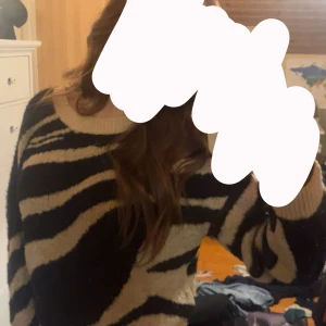 Zebramönstrad stickad tröja från ONLY - Säljer en supermysig stickad tröja från ONLY med zebramönster i svart och beige. Tröjan har rund halsringning, ribbade muddar och är långärmad. Superfin på och har en bra passform. Den är lite trasig uppe i höger axel men det syns inte när man har tröjan på sig! 