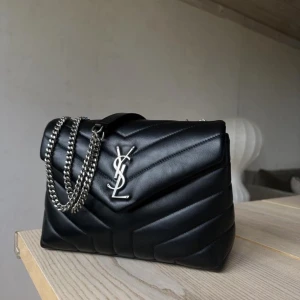  YSL Lou Lou  - Säljer en svart quiltad axelväska från YSL i skinn med silverfärgad kedja och YSL-logga framtill. Väskan har ett stort fack, innerficka med dragkedja och magnetlås. Väskan har lite skavanker då den är älskad💞Har tyvärr inget kvitto men kan skicka bild på serienummer💞