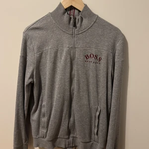 Grå hoodie från Hugo Boss - Grå hoodie från Hugo Boss med broderad logga på bröstet. Storlek M