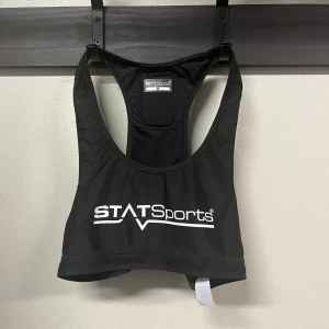 Svart sporttopp från STATSports - Sportig svart linnetopp från STATSports med vitt tryck framtill. Modellen är ärmlös med brottarrygg och elastisk nederkant för extra komfort. Perfekt för träning eller fotboll, tillverkad i lätt och stretchigt syntetmaterial.