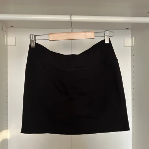 Svart kort kjol som går att vika - Svart kort kjol som går att vika ner kanten och göra low waist. S men stretchig
