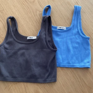2 ribbade linnetoppar - Två croppade linnetoppar från FB Sister/new yorker i storlek S. En är ljusblå och den andra är mörkgrå, båda i ribbad bomullsmix med breda axelband och rundad hals. 45 för båda