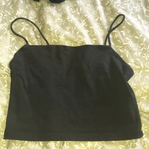 Svart linnetopp från Bik Bok - Enkel och stilren svart linnetopp från Bik Bok i storlek S. Toppen har smala axelband och är croppad i modellen, perfekt till höga jeans eller kjol. Mjuk och stretchig bomullskänsla som gör den superbekväm att bära.