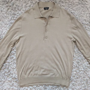 Beige pikétröja från Massimo Dutti - Stilren beige pikétröja från Massimo Dutti i 100% bomull. Tröjan har lång ärm, klassisk krage.