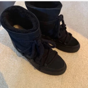 Svarta Inuikii boots med snörning - Svarta boots från Inuikii med grov snörning och fluffigt foder. Skorna har en rund tå, platt sula och är tillverkade i mocka och skinn. Perfekta för kalla dagar med sin varma insida och trendiga look. De säljer jag för att jag tänkte köpa ett par bruna denna vinter. Köpt för 3 940 och används två vintrar (därför lite slitna, se sista bilden) och därav priset! ☺️