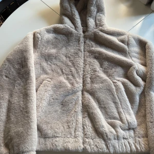 Beige pälsjacka med huva från HM - Mysig beige pälsjacka från HM i nyskick!