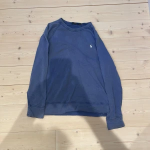 Blå sweatshirt från Polo Ralph Lauren - Säljer en blå sweatshirt från Polo Ralph Lauren med klassisk broderad logga på bröstet. Tröjan har rund halsringning och långa ärmar. Perfekt för en avslappnad och stilren look. Skick 9/10. Storlek L men passar även M, det är bara att skriva om ni undrar något!