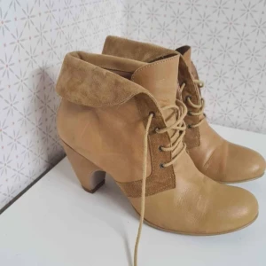 Beiga boots med snörning och klack - Snygga beiga boots med snörning och vikbar krage i äkta mocka Skorna har en rund tå och en stabil klack, tillverkade i en mix av skinn och mocka. Perfekta för dig som vill ha en stilren och trendig look.