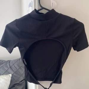 Svart ribbad croppad topp från Gina Tricot - Säljer en svart ribbad croppad topp från Gina Tricot med öppen rygg. Aldrig använd. (Tvättas innan)