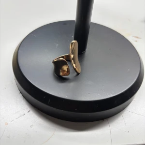 Guldfärgad öppen ring med organisk form - Säljer en stilren guldfärgad ring med öppen design och mjukt böjda former. Perfekt för dig som gillar minimalistiska och moderna smycken. Ringen är justerbar och passar de flesta storlekar.
