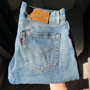 Levi's 511 blå jeans - Säljer ett par klassiska blå Levi's 511 jeans med normal passform och raka ben. Jeansen har fem fickor, läderpatch bak och den ikoniska röda Levi's-taggen på bakfickan. Perfekta för dig som gillar en tidlös denimlook.