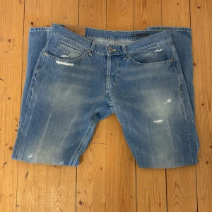 Ljusblå skinny jeans från Dondup  - Säljer ett par ljusblå skinny jeans från Dondup med slitna detaljer och klassisk femficksdesign. Jeansen har dragkedjegylf och en smal passform som sitter tajt längs benen. Perfekta för en avslappnad och trendig look.