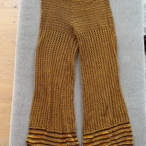 Gul-lila stickade byxor från Stockholm Atelier &Other Stories - Säljer ett par unika stickade byxor från Stockholm Atelier/& Other stories i gul och lila. Byxorna har vida ben och ett coolt mönster med ränder längst ner. Perfekta för dig som vill sticka ut med din stil! Hippie bohostil. 100% bomull. 