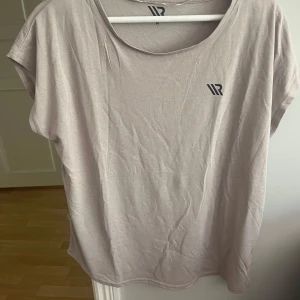 Ljusbeige t-shirt från WR - En basic ljusbeige t-shirt från WR med rund halsringning och diskret logga på bröstet. T-shirten har korta ärmar och är tillverkad i mjuk bomull, perfekt för en avslappnad stil.
