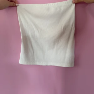 Vit ribbad tubtopp - Säljer en enkel och stilren vit ribbad tubtopp. Perfekt att matcha med jeans eller kjol för en clean look. Mjuk och stretchig i materialet för en bekväm passform. Använd.