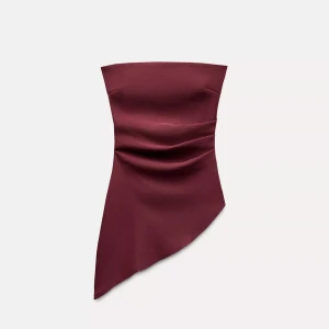 Vinröd asymmetrisk tubtopp - Säljer en vinröd tubtopp med asymmetrisk nederkant och draperad effekt framtill. Toppen är axelbandslös och har en dragkedja längst Eda sidan, den har en elegant, stilren look som passar perfekt till trendiga outfits. Den är liten i storleken.🥰