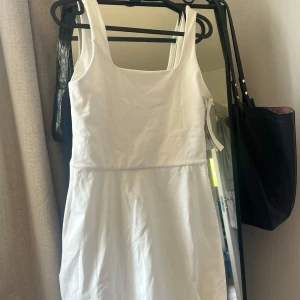 Vit ärmlös klänning från H&M Move - Oanvänt  vit klänning från H&M Move i storlek S. Klänningen är ärmlös med breda axelband och har en enkel, rak passform. Perfekt för varma dagar och enkel att styla med accessoarer.       OBS! Det är foundation fläck på 