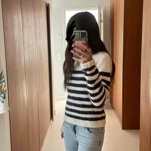 Randig stickad tröja i vitt och marinblått - Mysig stickad tröja jätte bra för sena sommarkvällar. Den är i strl S men passar även XS och M. Prislapp sitter kvar