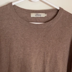 Beige stickad tröja från Lamous - Mjuk och stilren beige stickad tröja från Lamous med rund halsringning och långa ärmar. Perfekt för lager-på-lager och passar till många olika outfits.