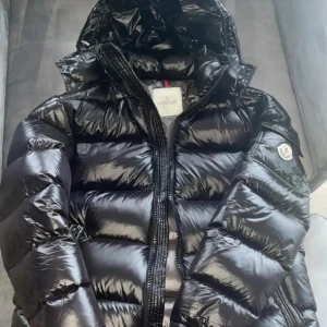 Svart Maya jacka Moncler - Säljer en glansig svart Maya jacka från Moncler . Jackan har en ficka med knapp och Moncler-logga på ärmen där Nfc Scan funkar🫶Jackan är såklart äkta och påse o lappar finns kvar. Säljer då den aldrig kommer till användning🫶 pris går o diskutera 