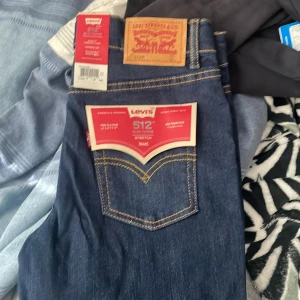 Levi's 512 Slim Taper Jeans - 2 för 1100 Mörkblå Levi's 512 jeans med slim passform och stretchmaterial. Klassisk femficksmodell med gul kontrastsöm och läderpatch bak i midjan. Perfekta för dig som gillar en smalare siluett och bekväm känsla.