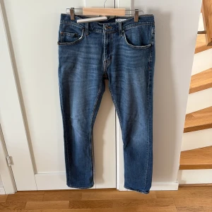 Blå jeans från Tiger of Sweden - Snygga blå jeans från Tiger of Sweden med klassisk femficksdesign och raka ben. Jeansen har normal passform och är tillverkade i ett slitstarkt denimtyg. Perfekta för en stilren och tidlös look.
