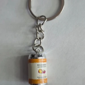 Nyckelring med Rekorderlig ciderburk - Säljer en unik nyckelring med en miniatyr av en Rekorderlig ciderburk. Perfekt accessoar för dig som gillar detaljer och vill ha något annorlunda på nyckelknippan. Färgerna är silver och orange med en tryckt etikett.