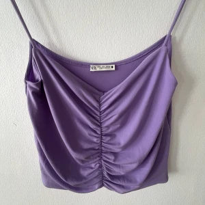 Lila croppad linnetopp från Zara - Säljer en lila croppad linnetopp från Zara med smala axelband och snygg rynkdetalj framtill. Mycket bra skick, har nästan aldrig använt den. Storlek S men skulle säga att den passar M med, den sitter ganska luftigt och axelbanden är långa.