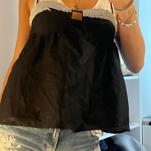 Svart glittrig linnetopp från Zara - Supersnygg svart linnetopp från Zara med tunna axelband och glittriga silverpaljetter längs bysten. Toppen har en luftig passform och en liten cut-out framtill. Perfekt för dig som vill sticka ut med lite extra bling.