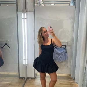 Svart kort klänning med volangkjol - Supersöt svart kort klänning med smala axelband och voluminös volangkjol. Storlek m. Pull and bear