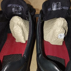 Svarta ECCO sneakers i skinn - Svarta sneakers från ECCO i mjukt skinn med snygga sömdetaljer och röd innersula. Skorna har snörning och en robust, mönstrad gummisula som ger bra grepp. Perfekta för dig som gillar stilrena och bekväma skor till vardags.                                                                                    Kan skickas med extra pris via post.                     