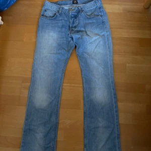 Ljusblå raka jeans från Lee - Säljer ett par klassiska ljusblå jeans från Lee med raka ben och femficksmodell. Jeansen har Lee-logga på bakfickan och är tillverkade i mjukt denimtyg. Perfekta för en avslappnad och stilren look.