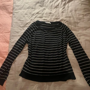 Marinblå-vit randig tröja från Zara - Snygg marinblå långärmad tröja från Zara med vita horisontella ränder. Tröjan har en klassisk rund halsringning och är tillverkad i ett mjukt, stickat material som sitter skönt på kroppen. Perfekt för dig som gillar stilrena och tidlösa plagg.