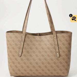 Beige väska från Guess - Stilren väska från Guess i beige med klassiskt logomönster över hela väskan. Väskan har långa axelband och rymmer allt du behöver till skolan ex. Väskan är i nyskick, endast använd vid två tillfällen. Inga skador, som ny. Kan skicka egna bilder vid intresse. Dustbag medföljer. 