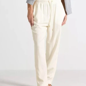 Vita linnebyxor med snörning - Snygga och luftiga krämvita linnebyxor med elastisk midja och snörning framtill. Byxorna har raka ben, sidfickor och en avslappnad passform som ger en chill vibe. Perfekta för varma dagar när du vill vara både bekväm och stilren. Aldrig använda och prislapp sitter kvar.