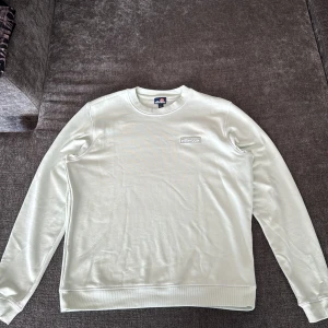 Grön sweatshirt från Ellesse - Säljer en stilren grön sweatshirt från Ellesse med broderad logga på bröstet. Tröjan har rund hals, kontrastfärgade sömmar, långa ärmar och ribbade muddar. Tillverkad i mjuk bomull och polyester för en skön känsla. Perfekt för dig som gillar enkel och clean streetstyle.